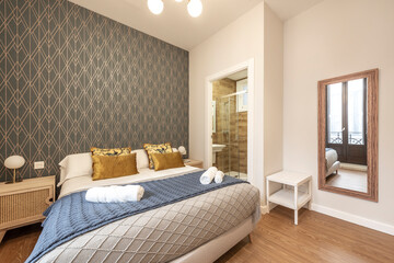 King bed with beautiful gold cushions, full-length mirror and bathroom with shower in the back in a vacation rental apartment