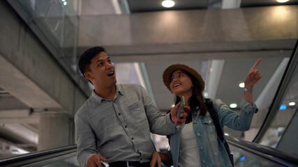 Couple Asian people in airport terminal waiting for  flight boarding.