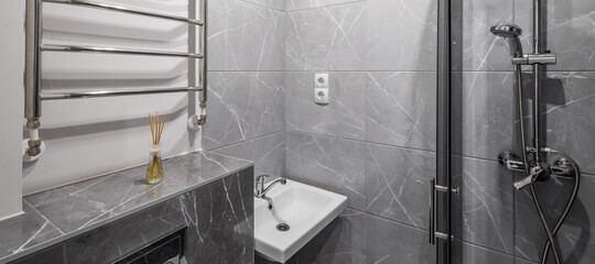 Modern interior of bathroom in luxury apartment. Grey marble tile. White sink. Shower cabin. Aroma...