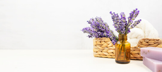 Fresh natural lavender in a glass bottle. Set for spa treatments with fresh lavender flowers on a white background. Banner, side view, place for text.
