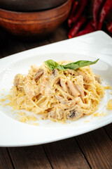 Carbonara paste with smoked chicken and mushrooms on wooden background