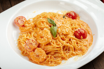 Spaghetti with shrimp and tomato cream sauce on a wooden background