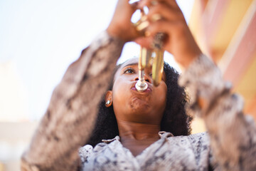 Low angle view of an african woman playing the trumpet in the city outside - obrazy, fototapety, plakaty