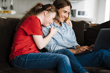 Woman and her daughter with down syndrome using laptop