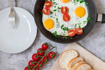Fried eggs in a frying pan. On a concrete gray background. On the plate