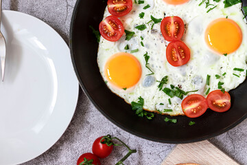 Fried eggs in a frying pan. On a concrete gray background. On the plate