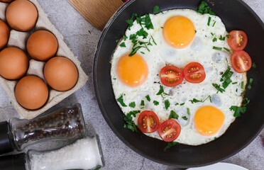 Fried eggs in a frying pan. On a concrete gray background. On the plate