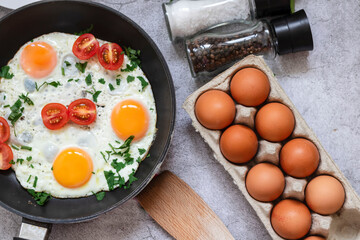 Fried eggs in a frying pan. On a concrete gray background. On the plate