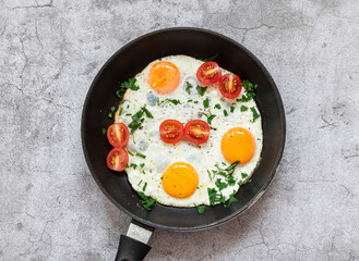 Fried eggs in a frying pan. On a concrete gray background. On the plate