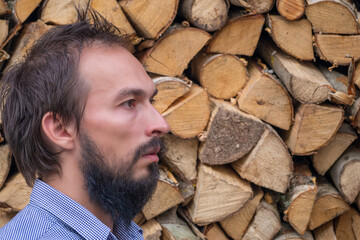 A man with a beard in profile against the background of a woodcutter