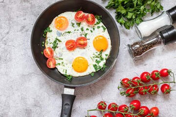 Fried eggs in a frying pan. On a concrete gray background. On the plate