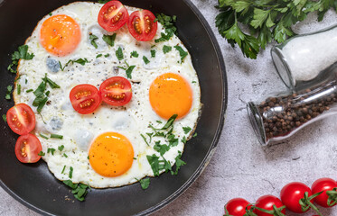 Fried eggs in a frying pan. On a concrete gray background. On the plate
