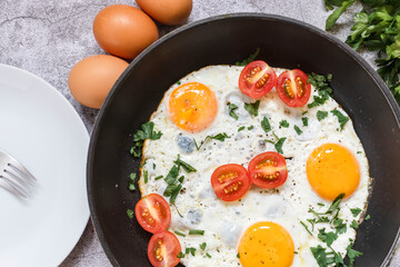Fried eggs in a frying pan. On a concrete gray background. On the plate
