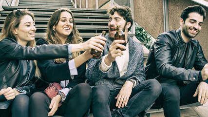 group of gen z young friends toasting with beers. Young people having fun raising bottled beers. Alcohol consumption concept. - obrazy, fototapety, plakaty
