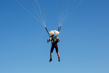 Fototapeta na wymiar Parachute in the sky. Skydiver is flying a parachute in the blue sky.