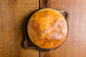 Khachapuri pie with cheese served on a wooden board over rustic wooden background. Georgian cuisine concept