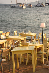 tables set for dinner on the beach at sunset over the sea in Aegina in Greece