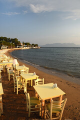 tables set for dinner on the beach at sunset over the sea in Aegina in Greece - 452486372