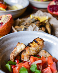 A dinner of fish and tomato salad served in a bowl on the table with other dishes.