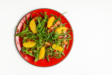 Delicious mixed vegetable and fruit salad served in a red plate over white background.
