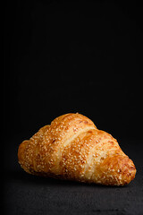 Croissant with sesame seeds isolated on dark background
