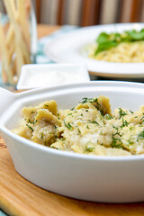Italian ravioli with spinach and cheese close-up, rustic style. Served in a white pan over rustic wooden board