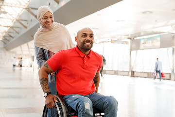 Fototapeta na wymiar Muslim woman and disabled man smiling together at train station