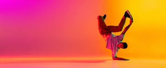 Foto auf Leinwand Flyer mit jungem, stylischem Mann, Breakdance-Tänzertraining in Freizeitkleidung einzeln auf rosafarbenem gelbem Hintergrund mit Farbverlauf im Tanzsaal im Neonlicht. © master1305