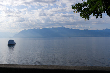Lake Geneva at Lausanne on a cloudy summer day with dramatic sky and beautiful sunbeams. Photo taken August 11th, 2021, Lausanne, Switzerland.