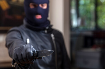 Burglar with balaclava, holding a knife in gloved hand, - obrazy, fototapety, plakaty