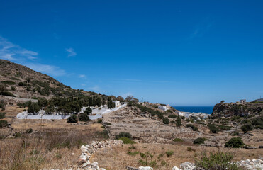 Fototapeta na wymiar Kimolos island, Chora village, Cyclades Greece. Cemetery at churchyard nature blue sky background.