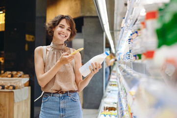 Young fun woman in casual clothes backpack shopping at supermaket store buy dairy produce take milk...