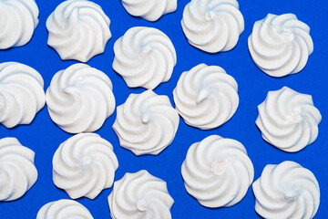 Closeup of french mini meringues cookies on dark blue as food background.