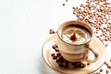 Latte and coffee beans on a white wooden table.
