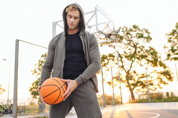 Serious minded sunlit young sporty sportsman man 20s in grey sports clothes hood look aside...