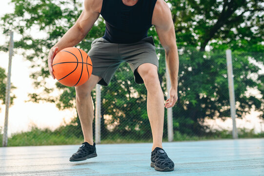 Cropped close up muscular young sporty sportsman man 20s wear black sports clothes training basketball ball handling drills play at basketball game playground court Outdoor courtyard sport concept.