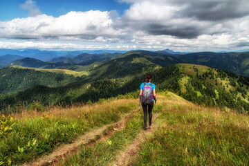 Fototapeta na wymiar Woman hiker with backpack and trekking poles on hiking trail