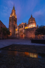 Cityscape in old city at sunset; Cathedral square in the old town of Toledo with reflection in the water of the fountain - artificial lake, World Heritage Site, Spain. Vertical view 