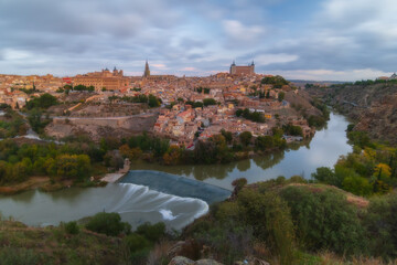 Fototapeta na wymiar Cityscape in old town with colorful clouds at sunset; Tagus river and old town of Toledo, World Heritage Site, Spain. Horizontal view