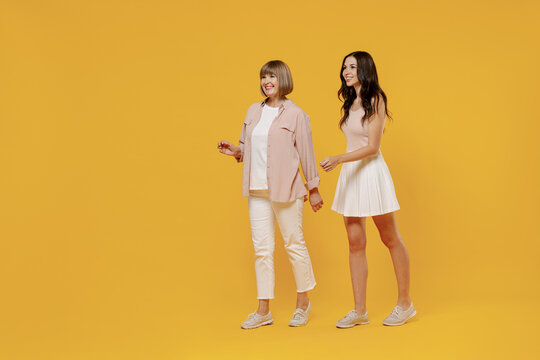 Full Body Side View Two Young Smiling Happy Daughter Mother Together Couple Women In Casual Beige Clothes Looking Camera Walk Isolated On Plain Yellow Color Background Studio Family Lifestyle Concept