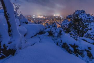 Night landscape of old city amidst fog, clouds and snow; Cathedral and Alcazar of Toledo in storm Filomena, World Heritage Site, Spain. Horizontal view