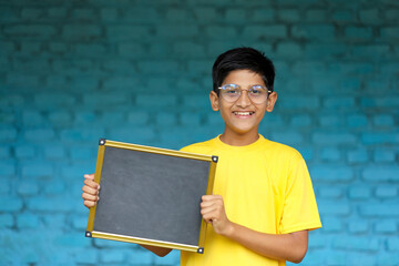 Indian little child showing chalkboard with copy space