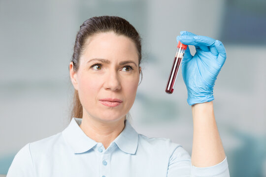 nurse or female scientist handling a blood sample in a test tube in a laboratory