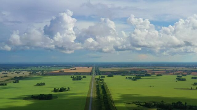 Magnificent landscapes of the fields from the drone.. Automobile road against the background of picturesque clouds. The road diagonally goes into perspective, cars are passing along the road.