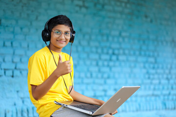 Indian child using laptop and headphone. attending online classes