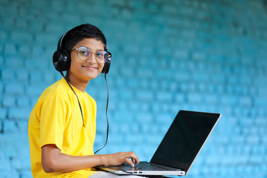 Indian Child Using Laptop And Headphone. Attending Online Classes