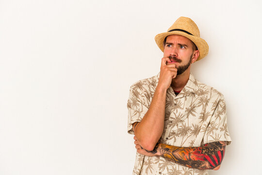 Young caucasian man with tattoos wearing summer clothes isolated on white background  relaxed thinking about something looking at a copy space.