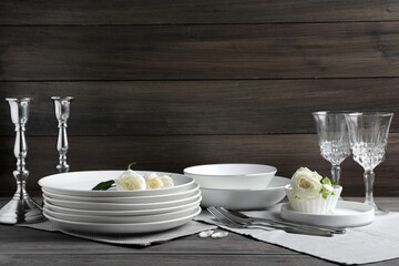 Set of clean dishware, cutlery and beautiful flowers on grey wooden table