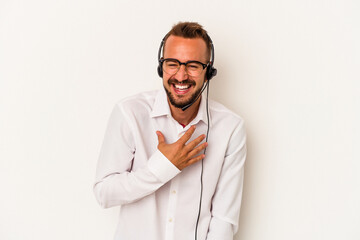 Young caucasian telemarketer man with tattoos isolated on white background  laughs out loudly keeping hand on chest.