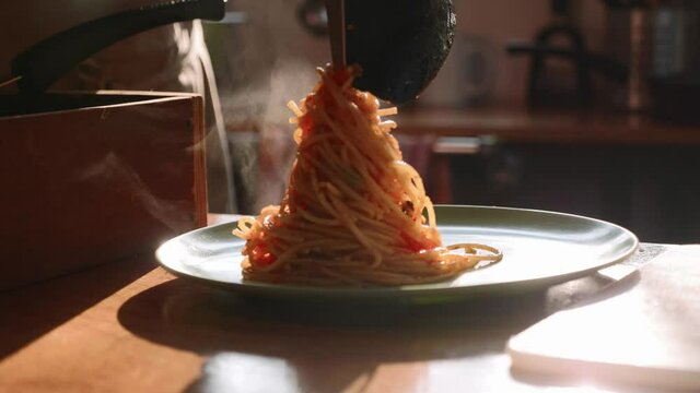 Cook serving spaghetti on the plate. Puts macaroni on the plate by fork